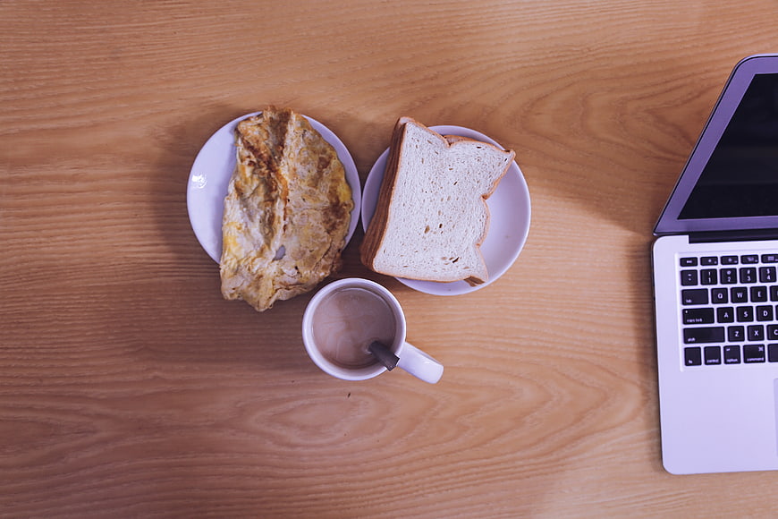 Flat lay breakfast with laptop on wooden desk