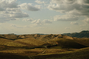 Rolling Hills Landscape with Winding Road and Cloudy Sky