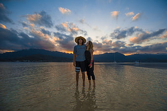Couple standing in shallow water at sunset beach