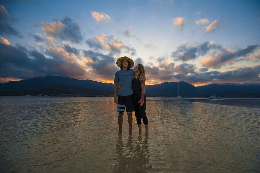 Couple standing in shallow water at sunset beach