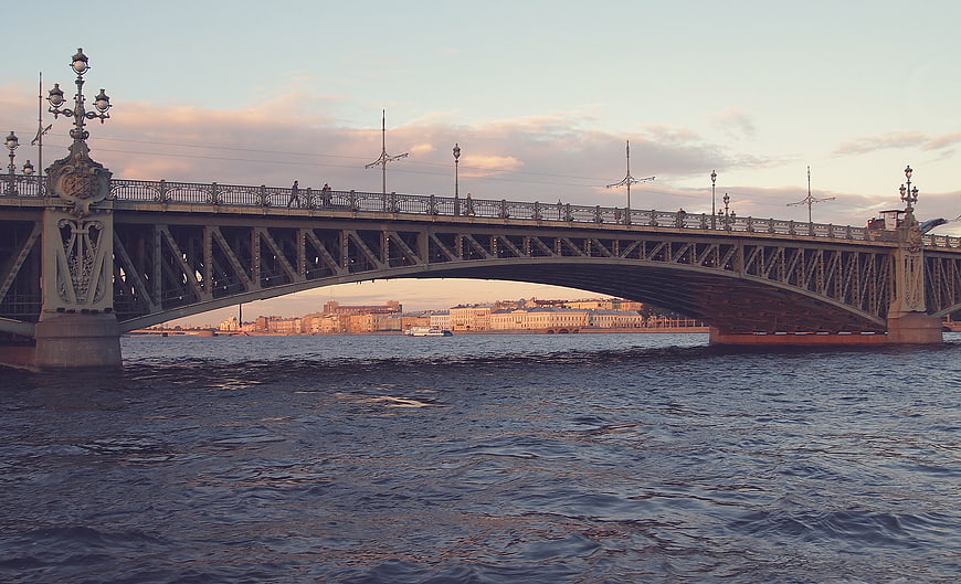 Iron Bridge Over River at Sunset with City Skyline