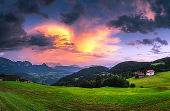Dramatic sunset over green alpine meadows and mountains