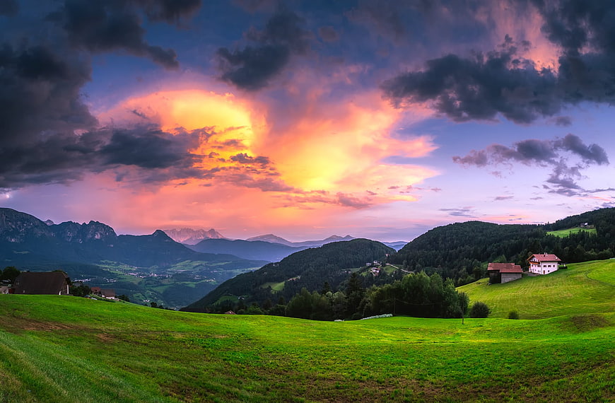Dramatic sunset over green alpine meadows and mountains