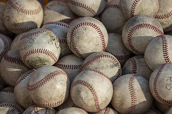 Close-up of dirty used baseballs with red stitching