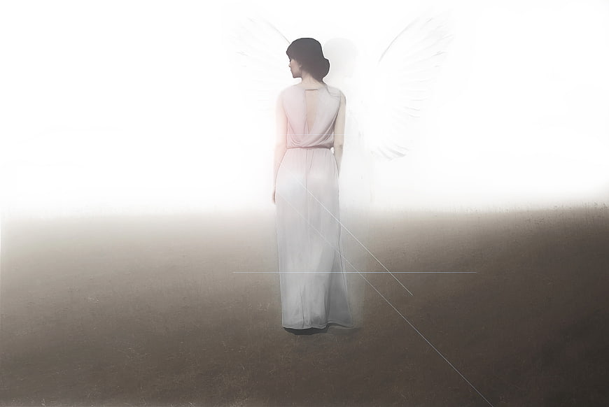 Woman with angel wings standing in bright light