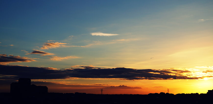 Dramatic sunset silhouette of city skyline and clouds