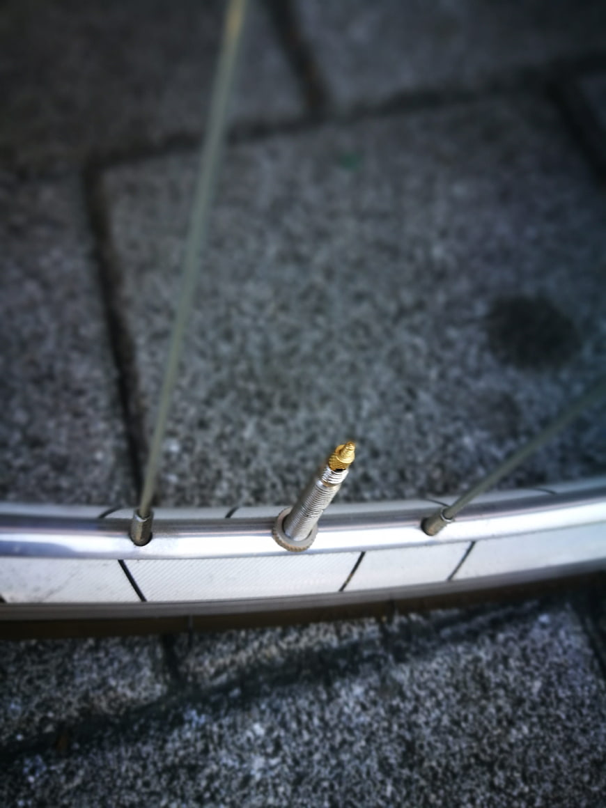 Close-up of bicycle wheel rim with brass Presta valve