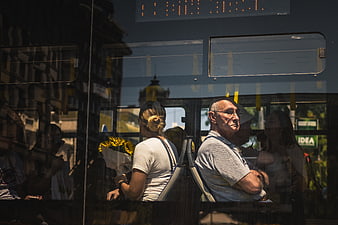 Passengers on a bus seen through window glass with reflections
