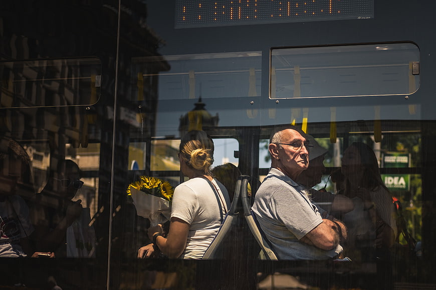 Passengers on a bus seen through window glass with reflections