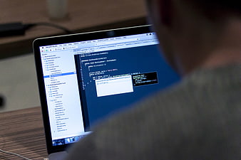 Programmer coding on laptop screen with code editor