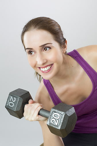 Smiling woman lifting 20lb dumbbell in purple tank top