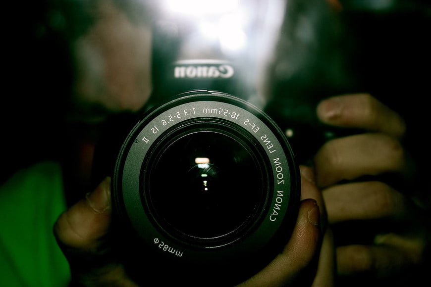 Close-up of Canon EOS 550D Camera Lens Held by Hands