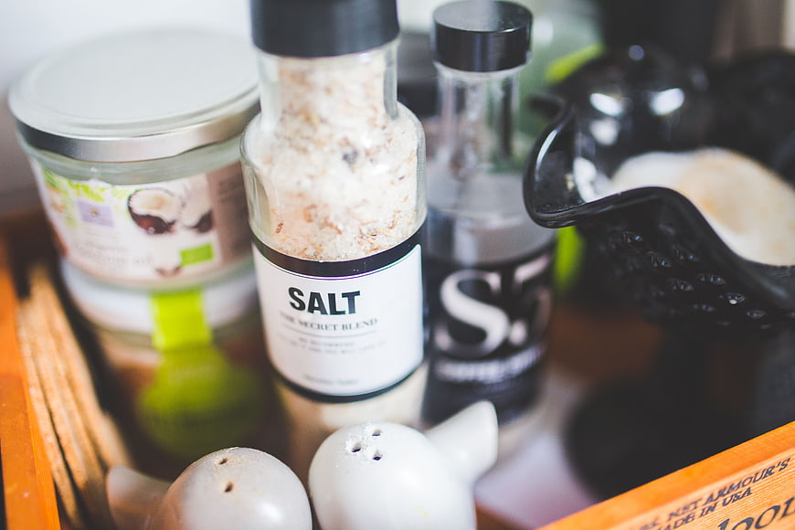Close-up of salt shaker and kitchen condiments in wooden tray