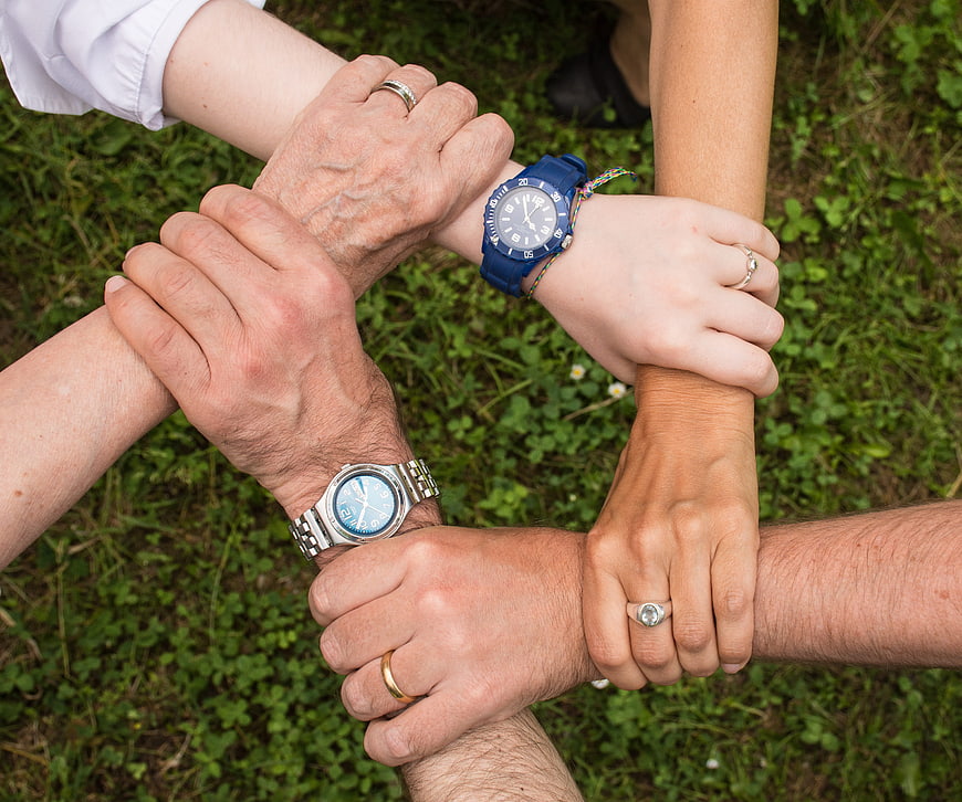 Multi-generational family hands clasped in unity circle
