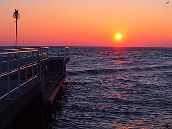 Vibrant Sunrise Over Ocean Pier with Calm Waves