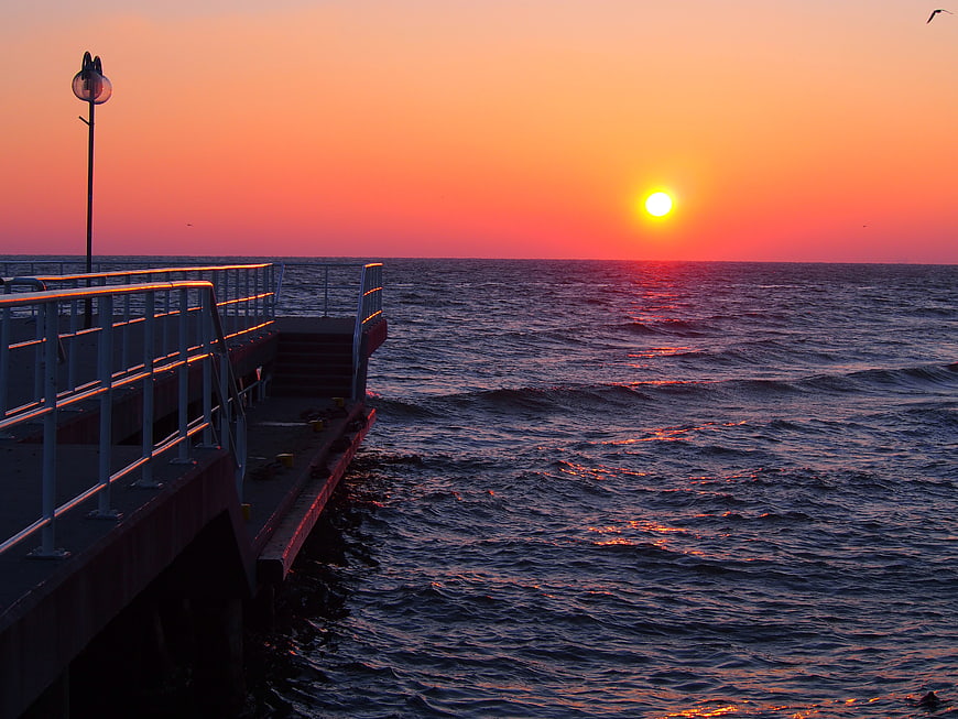 Vibrant Sunrise Over Ocean Pier with Calm Waves