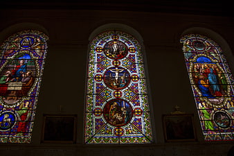 Three ornate stained glass windows in a church interior