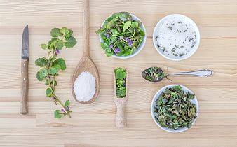 Flat lay of fresh herbs, salt, and kitchen utensils on wood