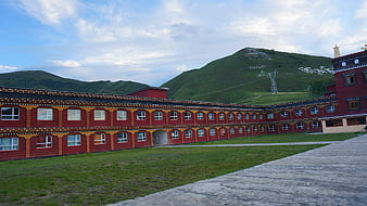 Traditional Tibetan monastery architecture with red walls and green hills