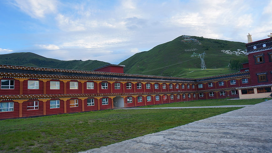 Traditional Tibetan monastery architecture with red walls and green hills