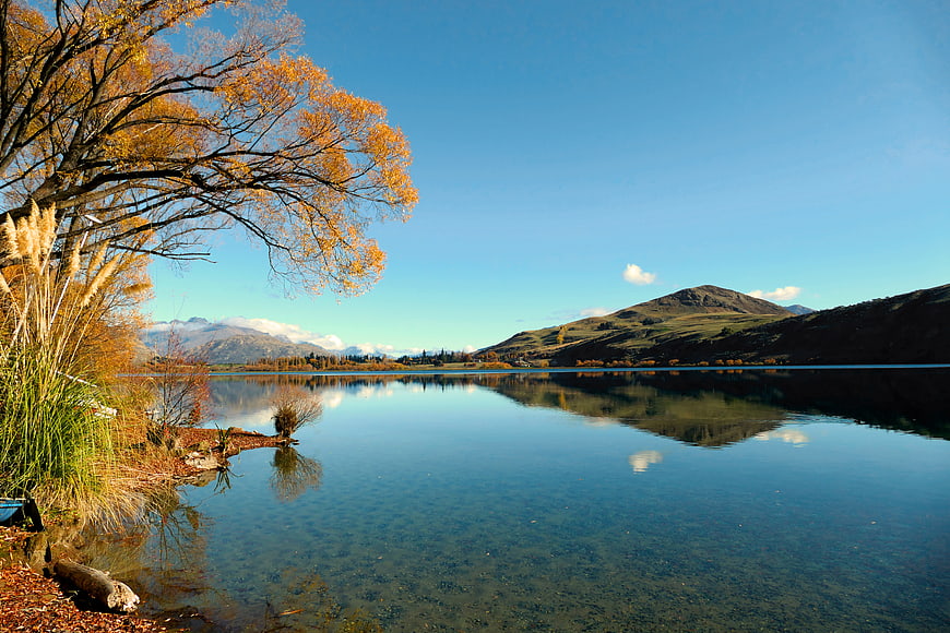 Serene Autumn Lake Landscape with Golden Trees and Mountain Reflections