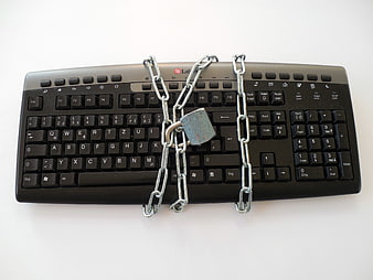 Black computer keyboard secured with metal chain and padlock