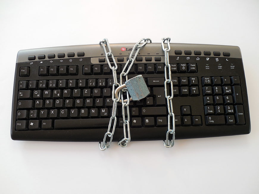 Black computer keyboard secured with metal chain and padlock
