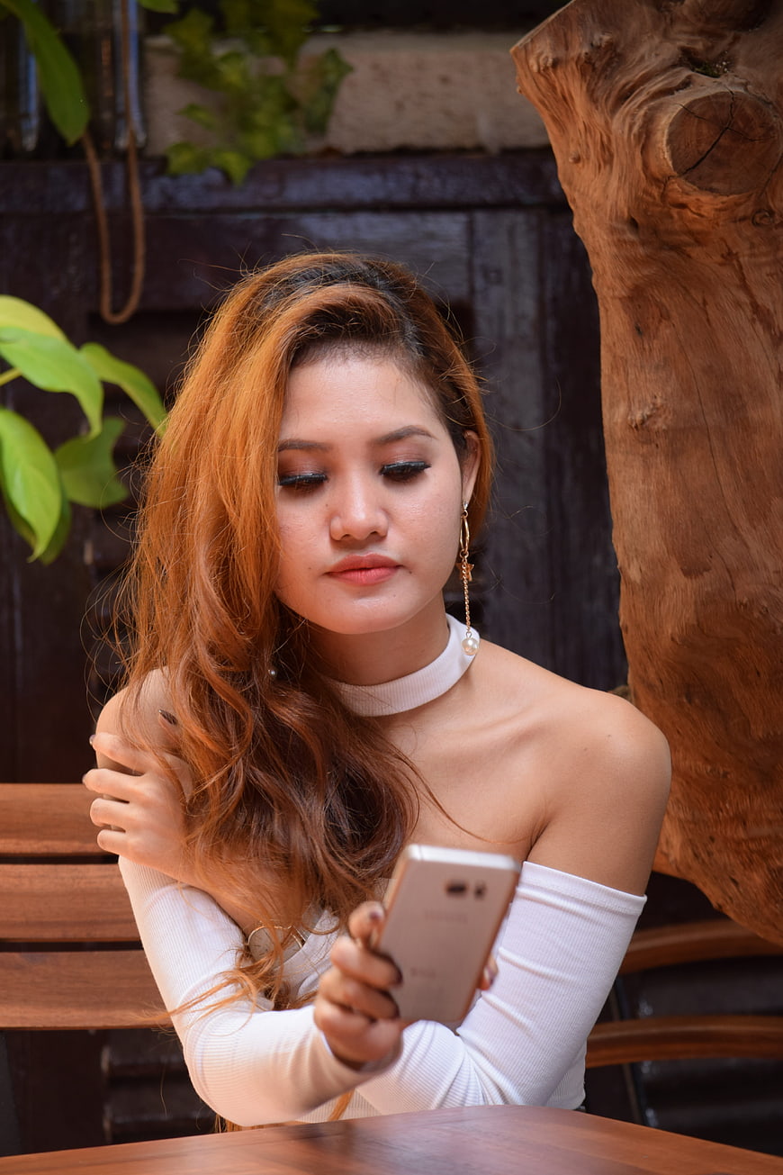 Young woman with orange hair looking at smartphone