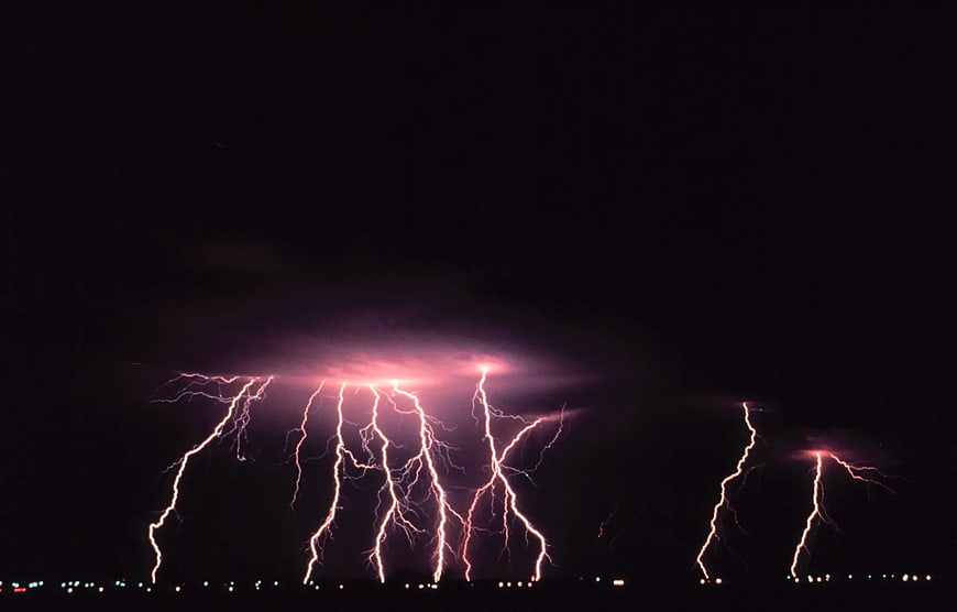 Dramatic Purple Lightning Storm Over City Lights at Night