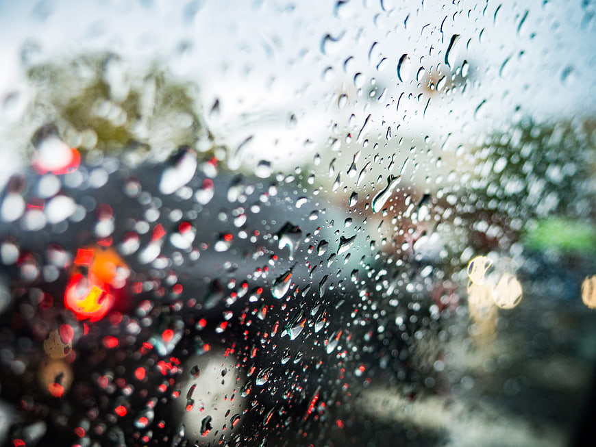 Raindrops on car windshield with blurred city lights