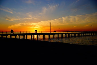 Silhouetted Couple Walking on Pier at Golden Sunset