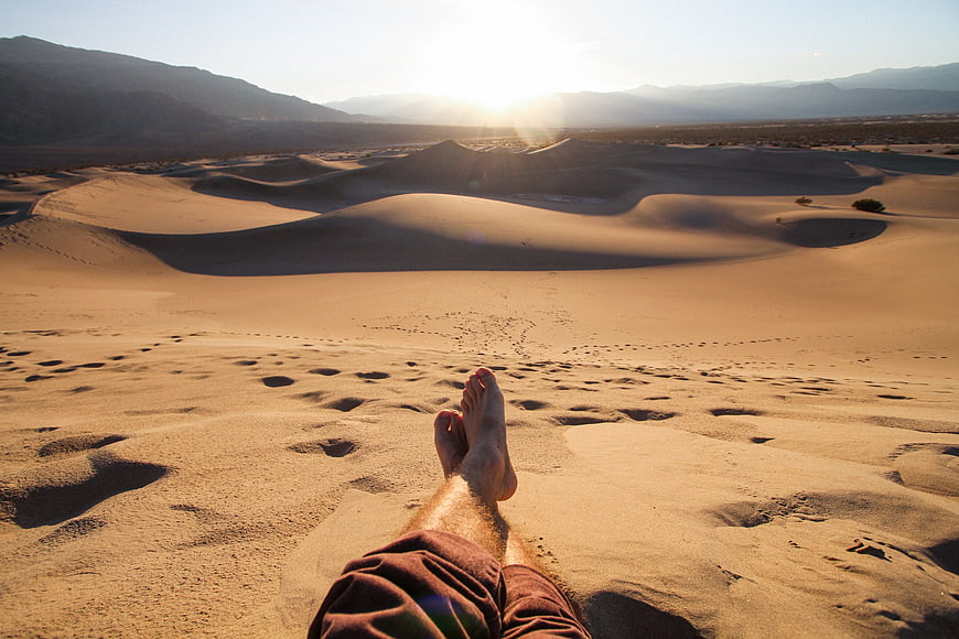 First Person View of Feet Relaxing on Sand Dunes at Sunset
