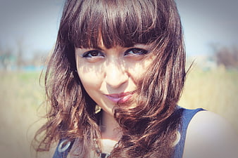 Close-up portrait of smiling young woman with brown hair outdoors