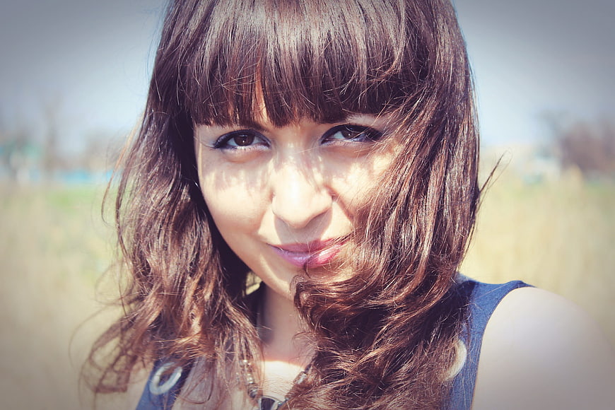 Close-up portrait of smiling young woman with brown hair outdoors