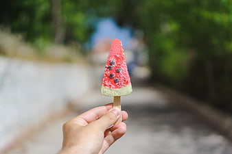 Hand holding watermelon popsicle outdoors