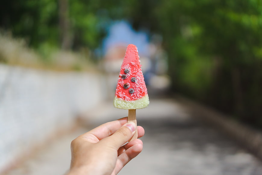 Hand holding watermelon popsicle outdoors