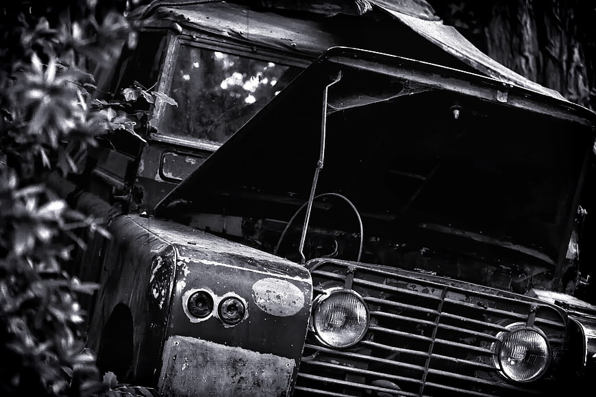 Abandoned vintage jeep with open hood in dense jungle foliage