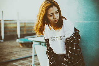 Asian woman leaning against teal wall outdoors