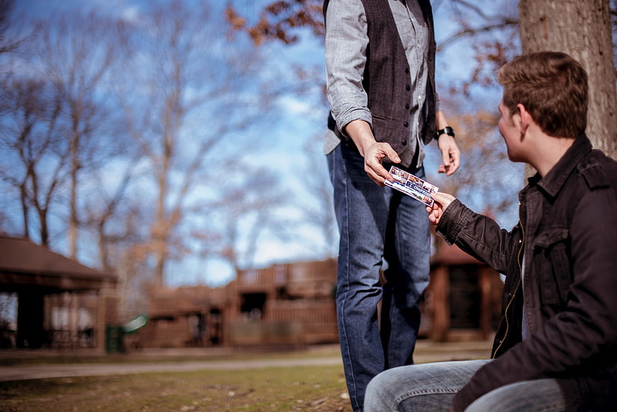 Two Men Exchanging Tickets in a Park
