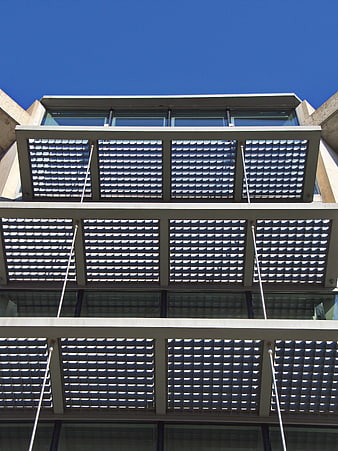 Modern building facade with geometric metal louvers and blue sky