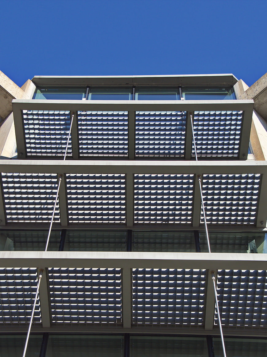 Modern building facade with geometric metal louvers and blue sky