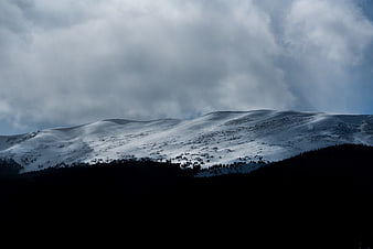 Dramatic Snow-Covered Mountain Ridge Under Stormy Clouds