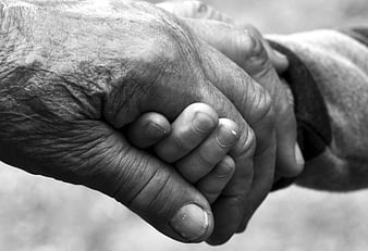 Black and white close-up of elderly hand holding child's hand