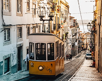 Yellow vintage tram on cobblestone street in Lisbon