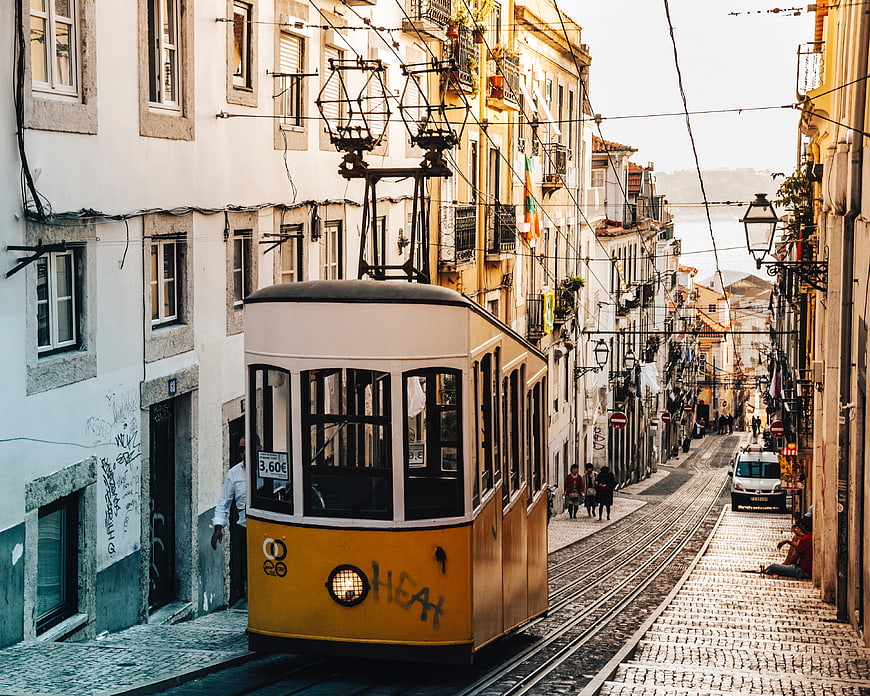 Yellow vintage tram on cobblestone street in Lisbon