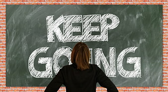 Woman looking at Keep Going written on chalkboard