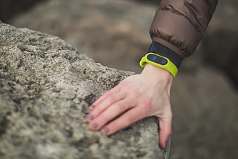 Hand with fitness tracker resting on textured rock outdoors