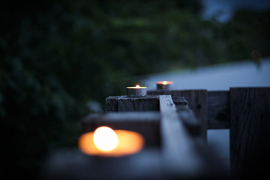 Tealight candles on wooden railing at dusk