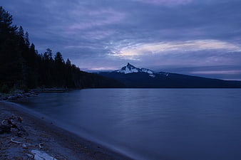 Serene Lake Shore at Dusk with Snow-Capped Mountain