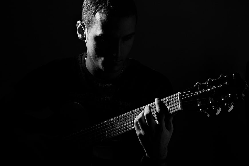 Dramatic black and white portrait of a man playing guitar